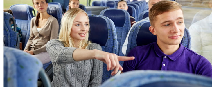 A tour guide speaks to tourists on a charter bus